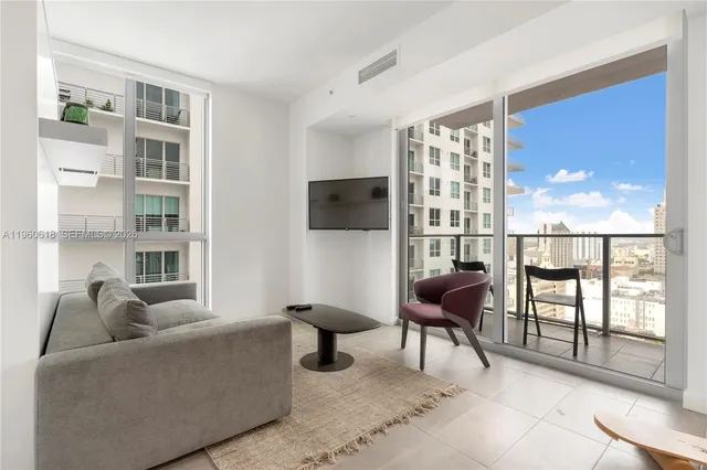 a living room with furniture a flat screen tv and a floor to ceiling window