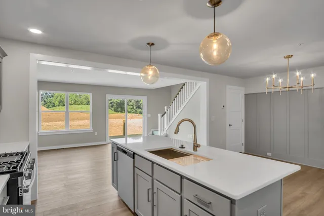 a view of a kitchen with granite countertop stainless steel appliances cabinets a sink and a chandelier