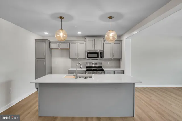 a kitchen with stainless steel appliances a refrigerator a sink dishwasher a stove and white cabinets with wooden floor