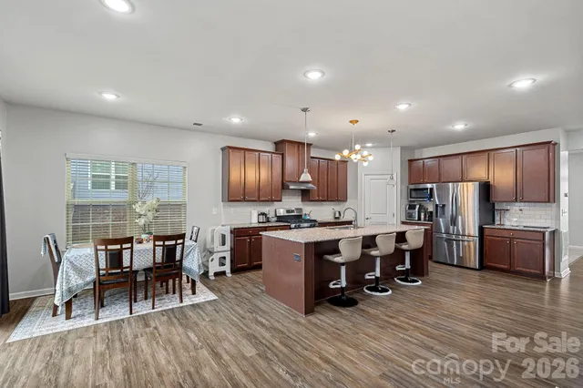 a large kitchen with kitchen island a island a stove a table and chairs in it