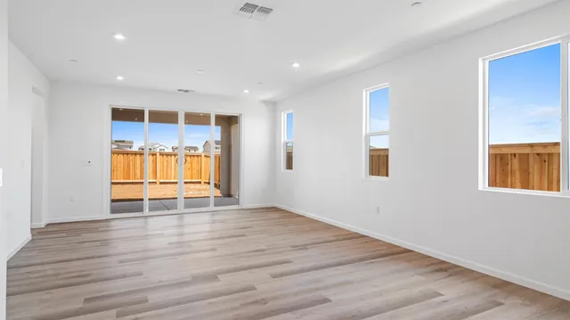 a view of an empty room with window and wooden floor