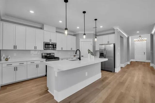 a view of a kitchen with kitchen island a sink stainless steel appliances and cabinets