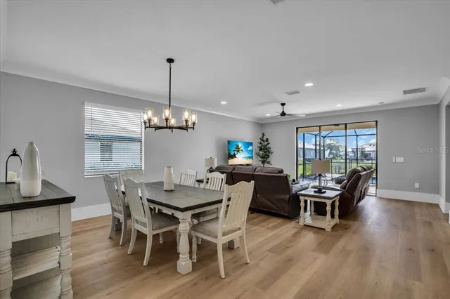 a view of a dining room and livingroom with furniture wooden floor a chandelier