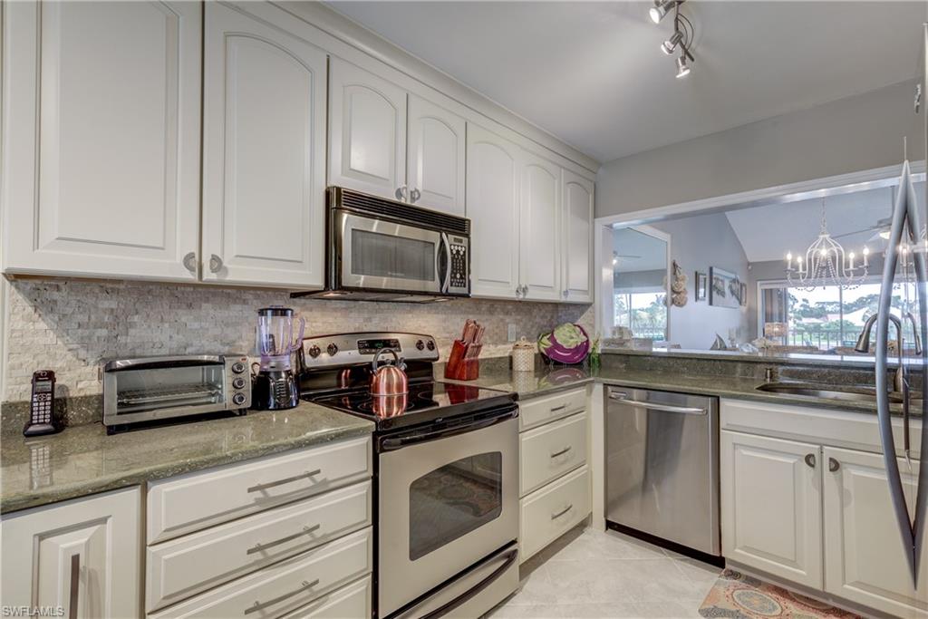760 Augusta Boulevard, Unit D204 Naples, FL 34113 - Photo 4 of 32 a kitchen with white cabinets stainless steel appliances and sink