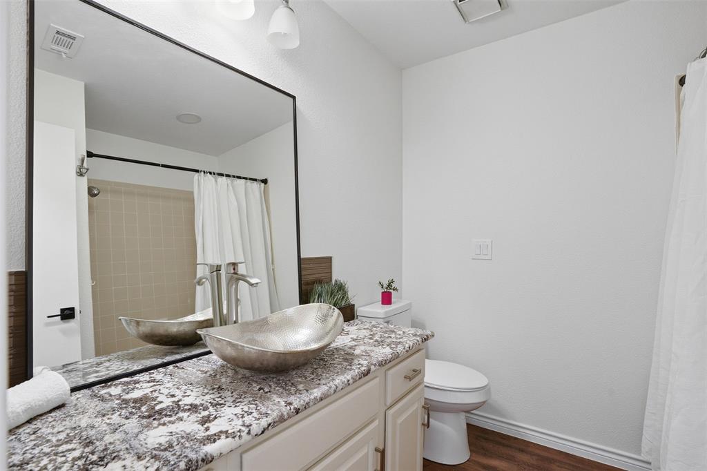 6500 Spur Ranch Court Plano, TX 75023 - Photo 17 of 32 a bathroom with a granite countertop sink a toilet and a mirror