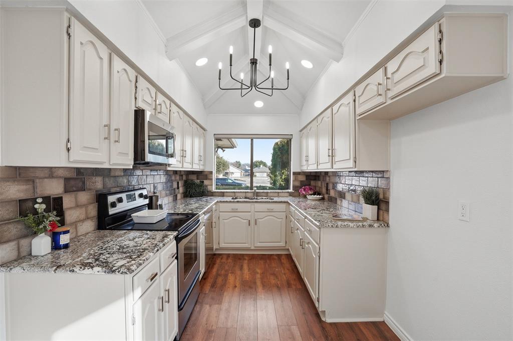 6500 Spur Ranch Court Plano, TX 75023 - Photo 7 of 32 a kitchen with kitchen island granite countertop stainless steel appliances lots of counter space sink refrigerator and cabinets