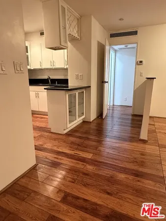 a view of an empty room with wooden floor and window