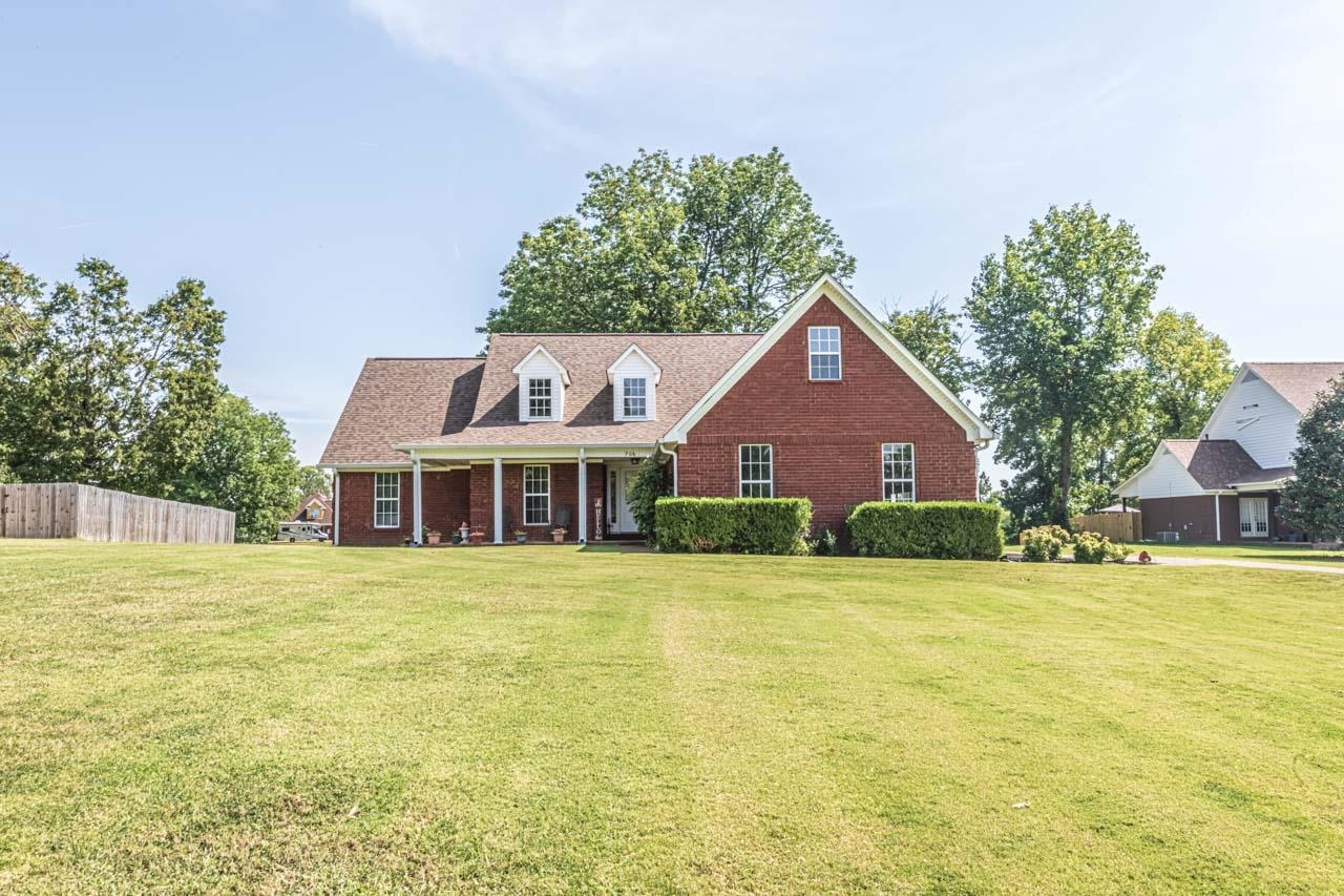 a front view of a house with a garden and trees