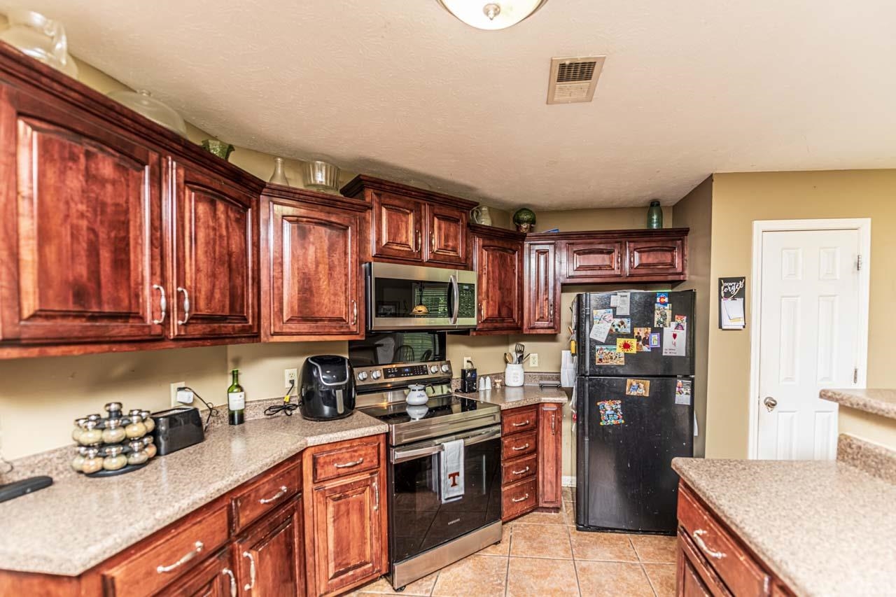 706 Liberty Church Smith Road Brighton, TN 38011 - Photo 14 of 35 a kitchen with stainless steel appliances granite countertop a stove top oven a sink dishwasher and a refrigerator with wooden cabinets
