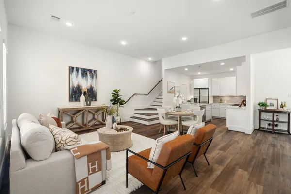 a living room with furniture kitchen view and a wooden floor