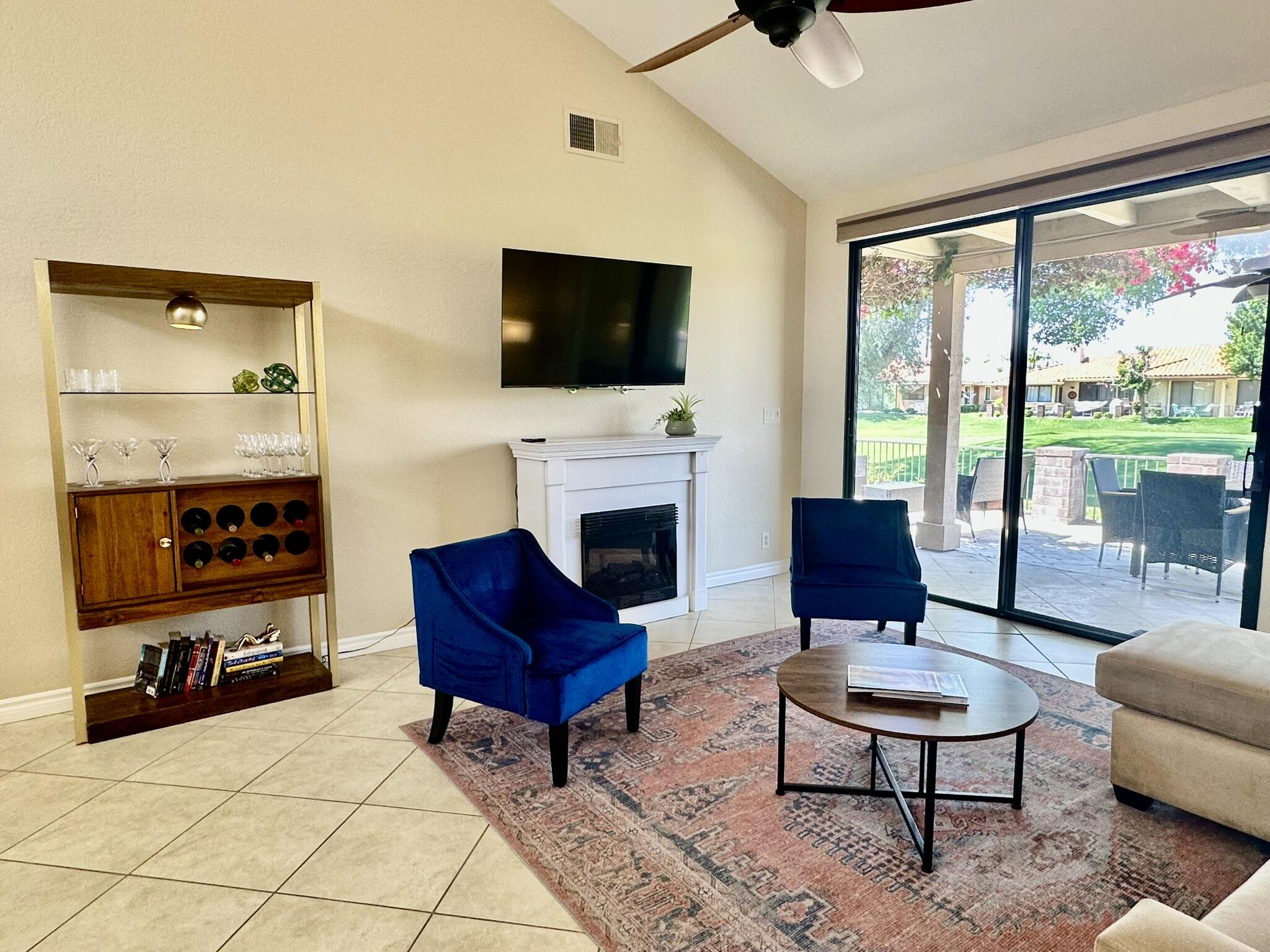 336 Villena Way Palm Desert, CA 92260 - Photo 8 of 19 a living room with furniture a flat screen tv and a fireplace