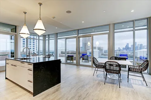 a kitchen with stainless steel appliances granite countertop a stove top oven a dining table and chairs with wooden floor