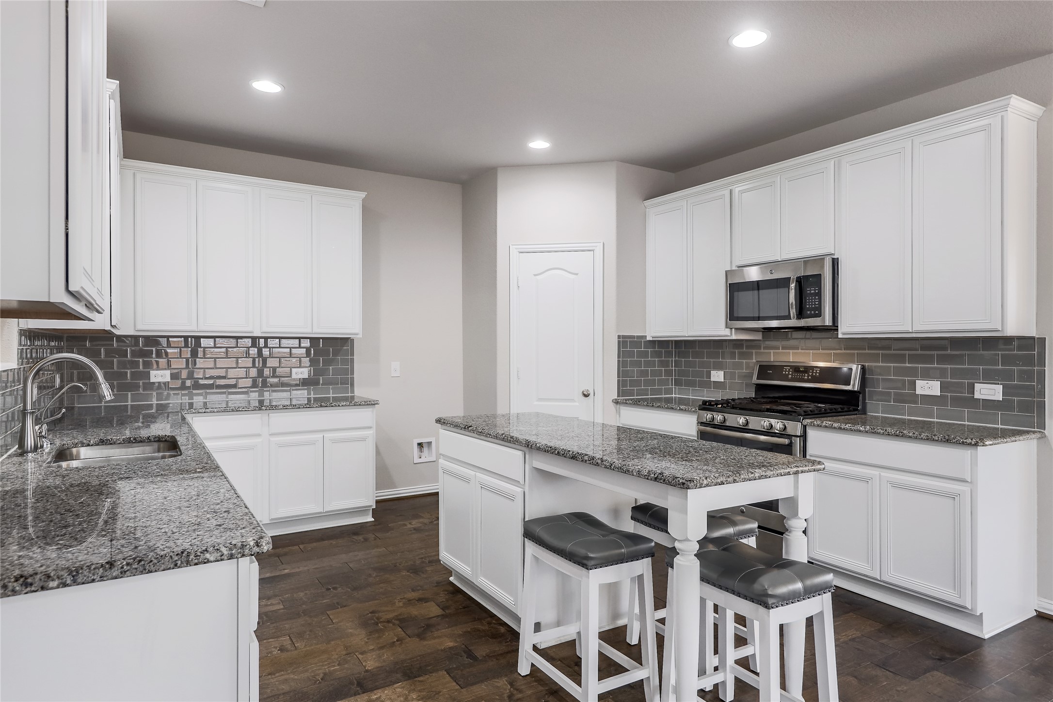 205 Penna Lane Georgetown, TX 78628 - Photo 9 of 32 A well-appointed culinary space featuring sleek white cabinetry, granite countertops, and modern appliances.