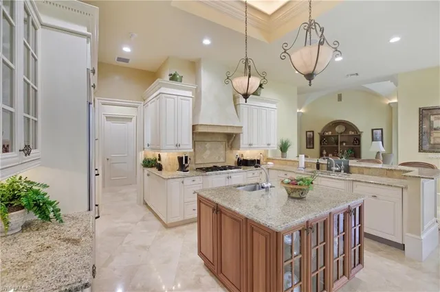 a kitchen with a stove center island a sink cabinets and living room view