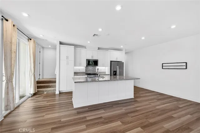 a large kitchen with stainless steel appliances granite countertop a large counter top and a wooden floor