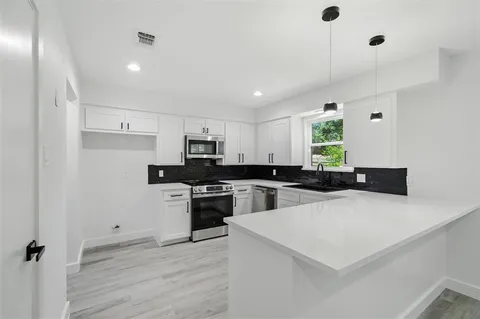 a kitchen with a refrigerator a stove a sink dishwasher a oven with white cabinets and wooden floor