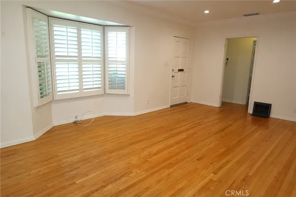 a view of an empty room with a window and wooden floor