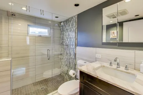 a bathroom with a granite countertop sink toilet a mirror and shower