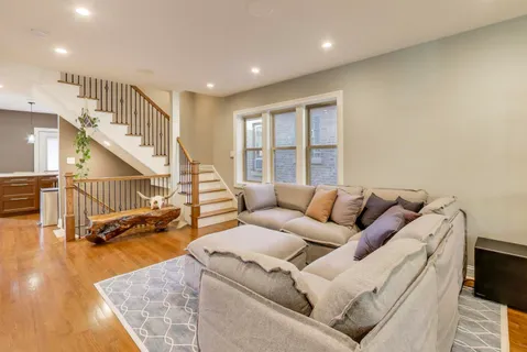 a living room with furniture and stairs with wooden floor