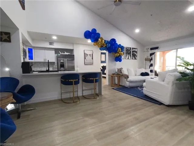 a living room with furniture and a dining table with kitchen appliances