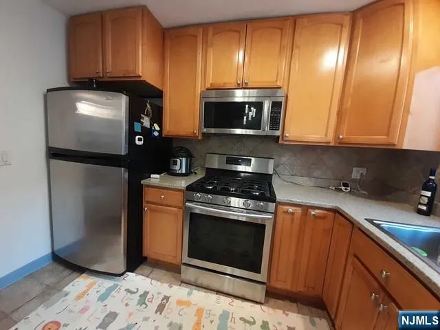 a kitchen with stainless steel appliances granite countertop a refrigerator a stove a sink and cabinets