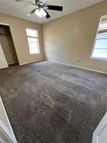 en empty room with windows and chandelier fan