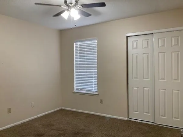 an empty room with windows and fan