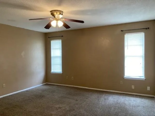 an empty room with a window and a chandelier fan