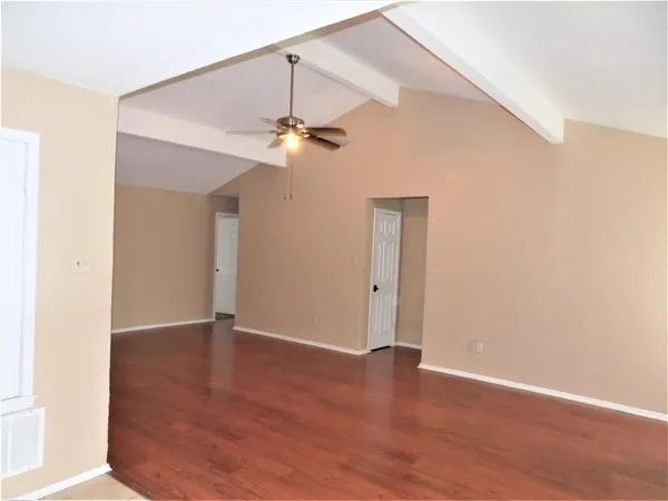 an empty room with wooden floor chandelier fan and closet area