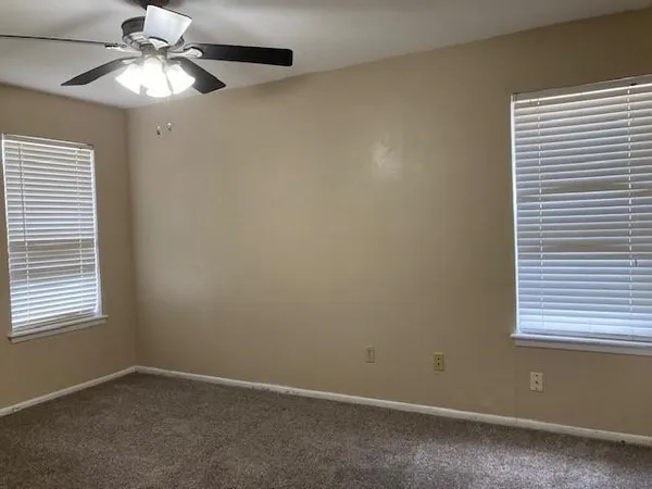 an empty room with a window and a fan