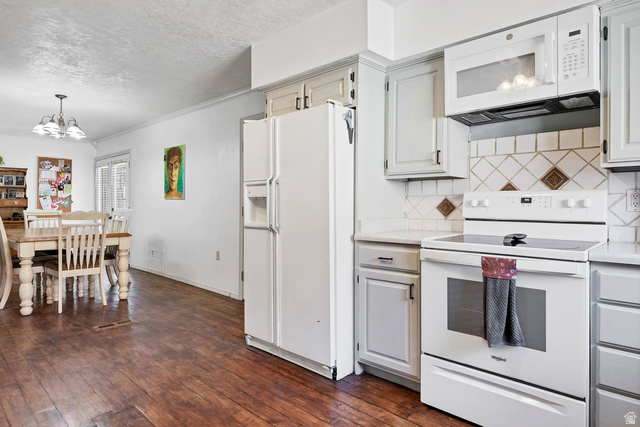 3334 Ute Road St. George, UT 84790 - Photo 9 of 40 Kitchen featuring white appliances, dark wood-type flooring, suspended lighting, a textured ceiling, and backsplash