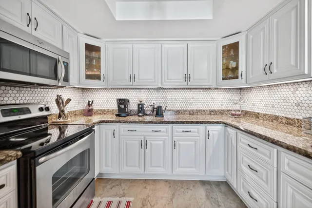 a kitchen with granite countertop white cabinets and stainless steel appliances