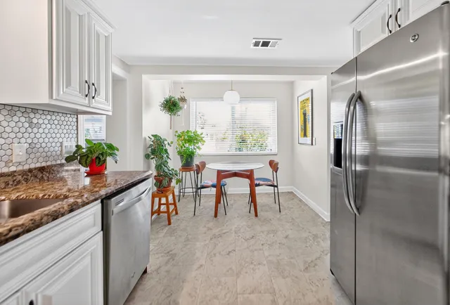 a kitchen with stainless steel appliances granite countertop sink a table and chairs in it