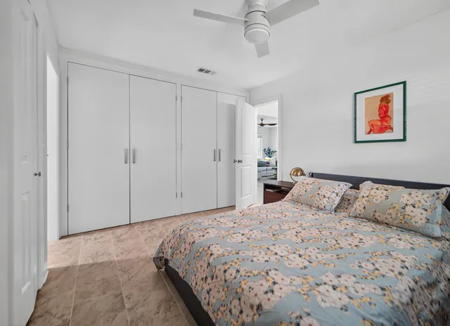 a bedroom with a large bed and a chandelier fan