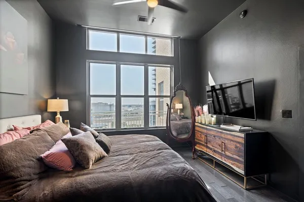 a bedroom with a bed a flat tv screen and a dresser