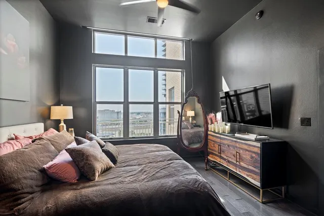 a bedroom with a bed a flat tv screen and a dresser