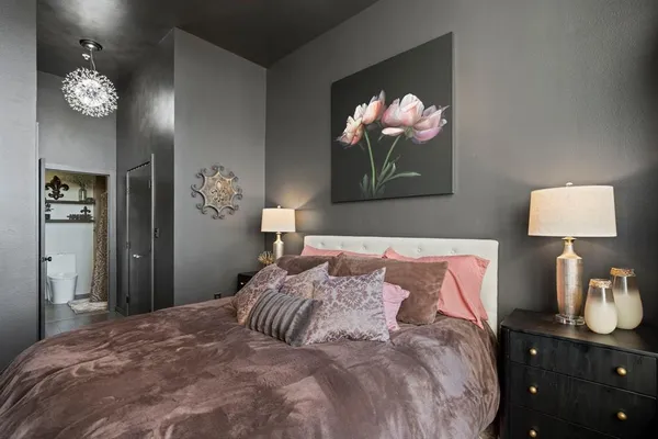 a bedroom with a bed and a lamp on dresser