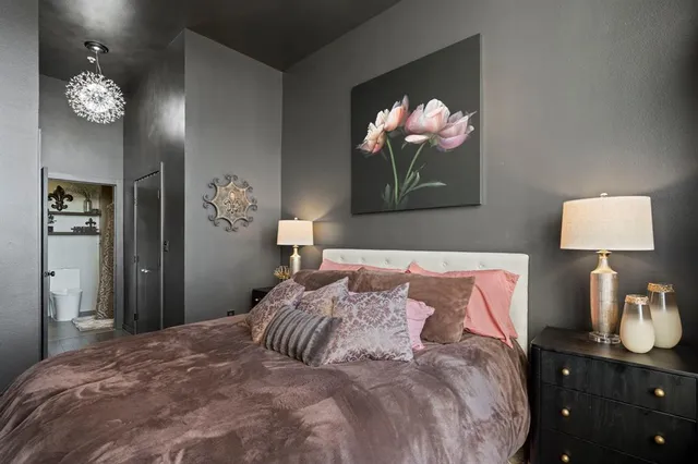 a bedroom with a bed and a lamp on dresser