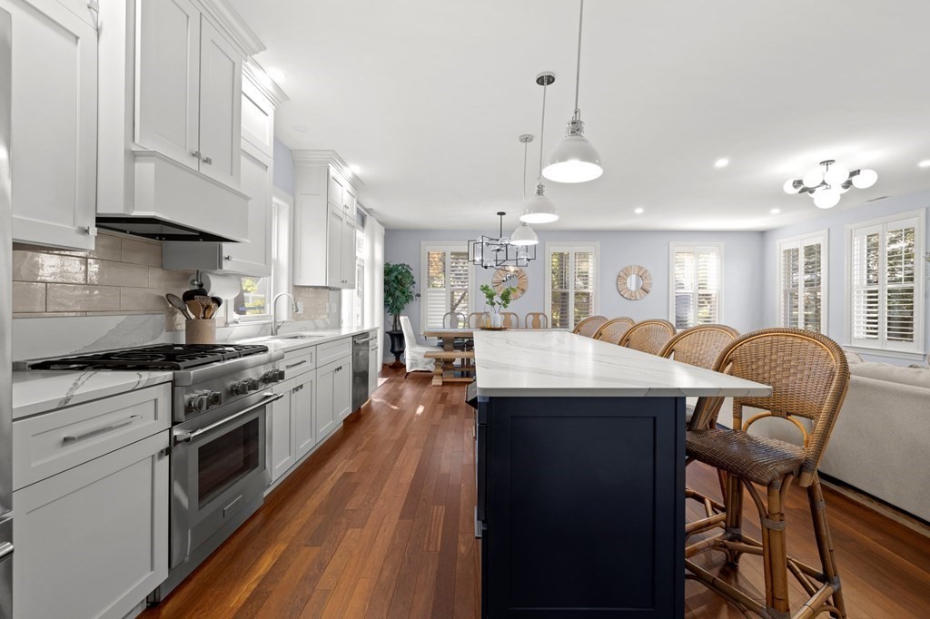 12 Big Rock Road Rye, NH 03870 - Photo 12 of 42 a kitchen with stainless steel appliances granite countertop a stove a sink dishwasher a dining table and chairs with wooden floor