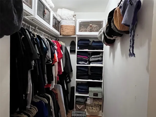 a view of walk in closet with clothes and shoes
