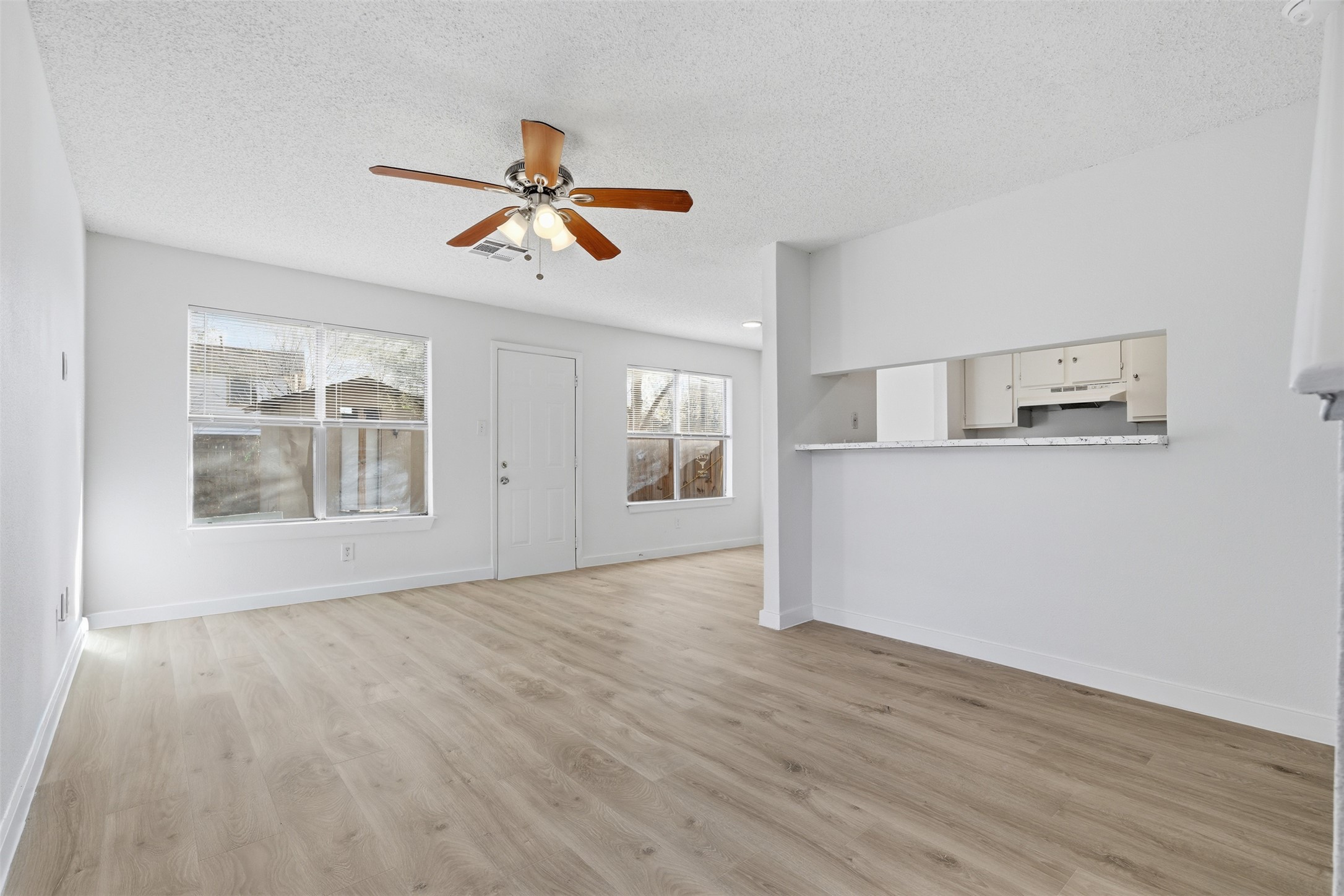 1605 Future Drive, Unit B Austin, TX 78754 - Photo 2 of 13 Unfurnished living room featuring ceiling fan, new light vinyl flooring, and a textured ceiling