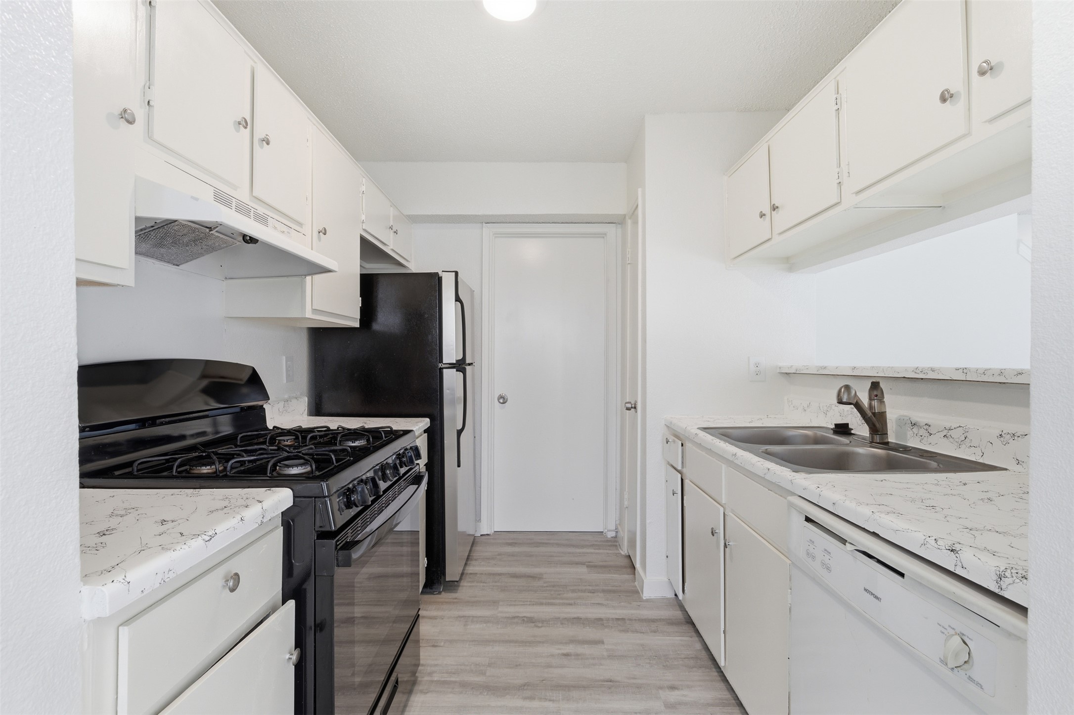 1605 Future Drive, Unit B Austin, TX 78754 - Photo 5 of 13 Kitchen with black range with gas stovetop, dishwasher, new granite countertops, and white cabinets
