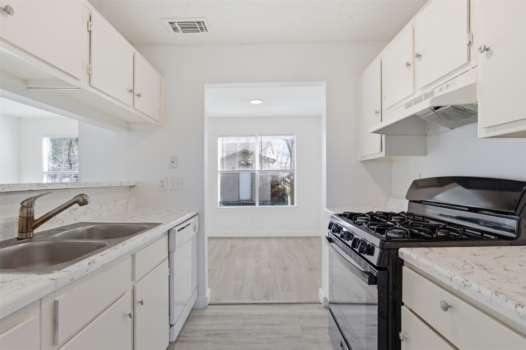 1605 Future Drive, Unit B Austin, TX 78754 - Photo 6 of 13 Kitchen featuring black range with gas cooktop, white cabinets, light countertops, and light wood-style floors