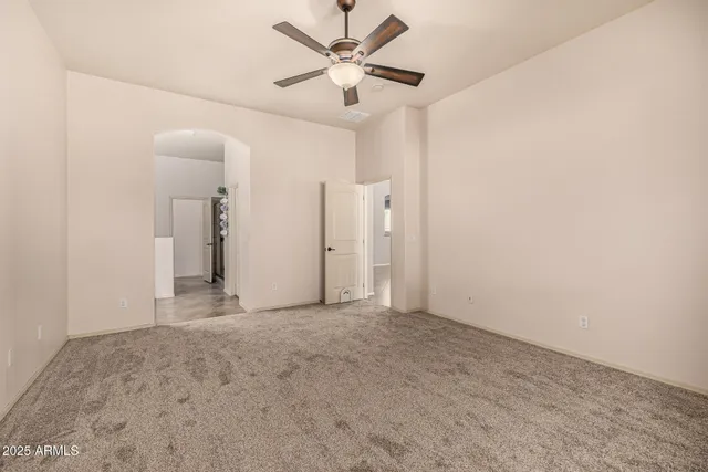 an empty room with windows and ceiling fan