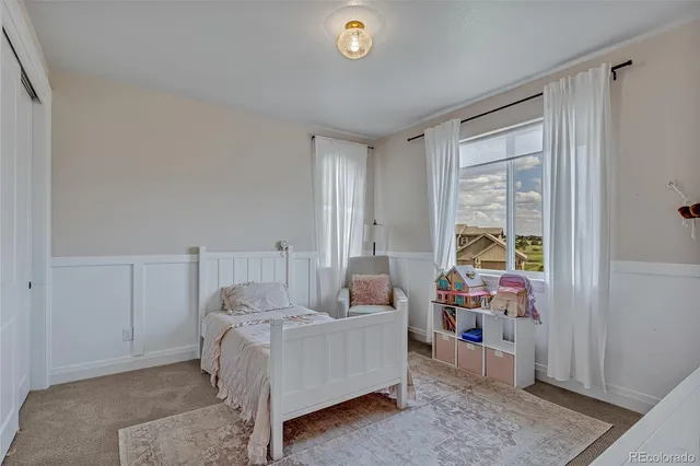a spacious bedroom with a bed painting on wall and a large window