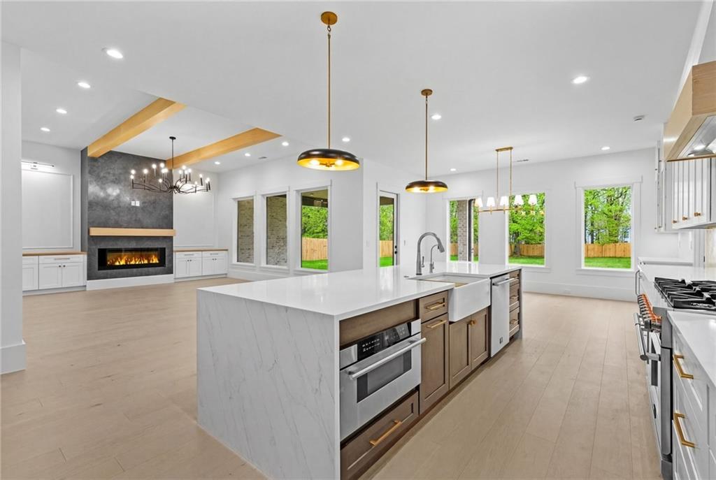 2865 Old Fountain Road Dacula, GA 30019 - Photo 14 of 84 a large kitchen with stainless steel appliances a large counter top a stove a chimney a sink and a large window