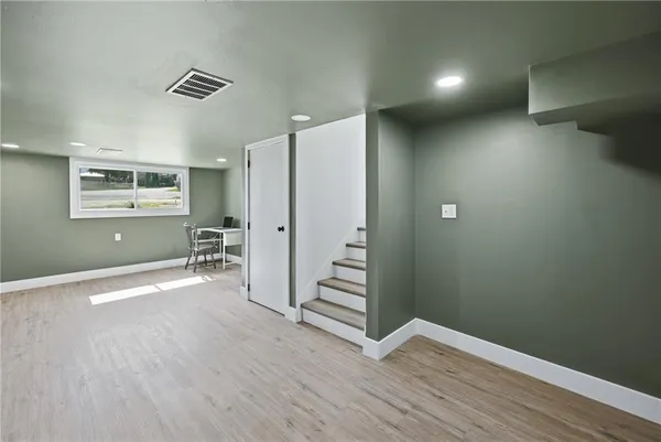 a view of an empty room with wooden floor and a ceiling fan