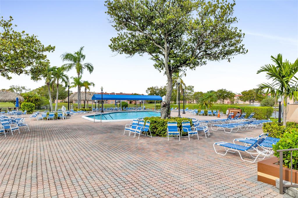 10145 Sunrise Lakes Boulevard, Unit 406 Sunrise, FL 33322 - Photo 32 of 37 a row of palm trees and a fire pit with large trees