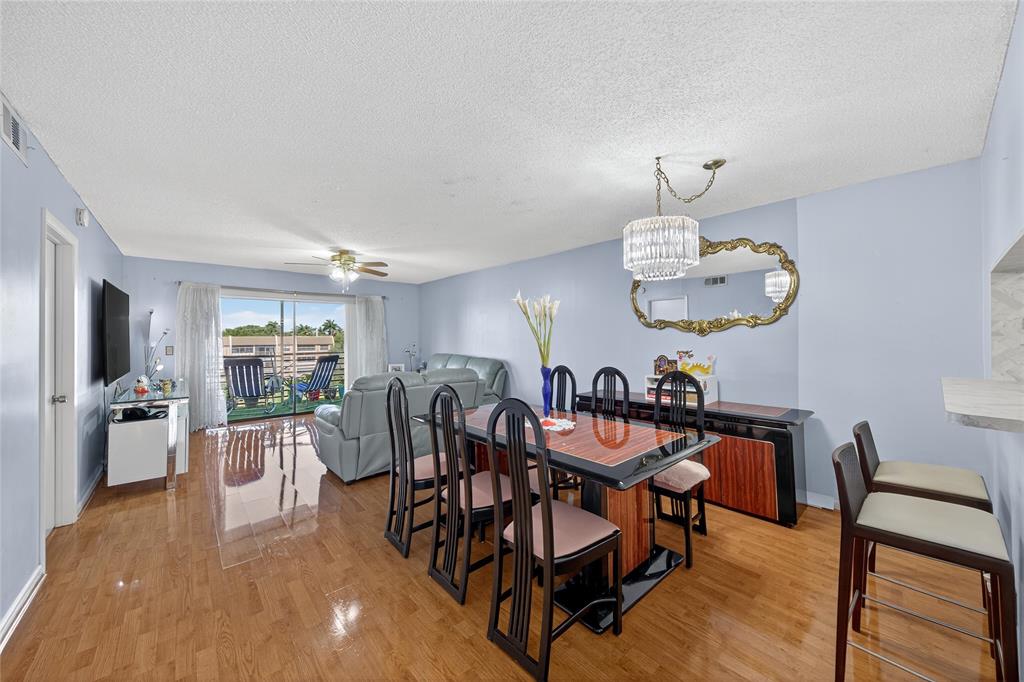 10145 Sunrise Lakes Boulevard, Unit 406 Sunrise, FL 33322 - Photo 6 of 37 a view of a dining room with furniture wooden floor and chandelier