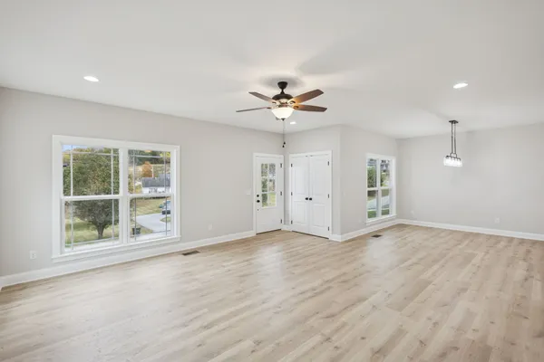 a view of an empty room with a window and wooden floor